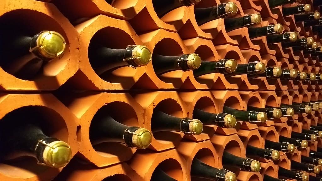 Bouteilles couchées dans les alvéoles en terre cuite de la cave