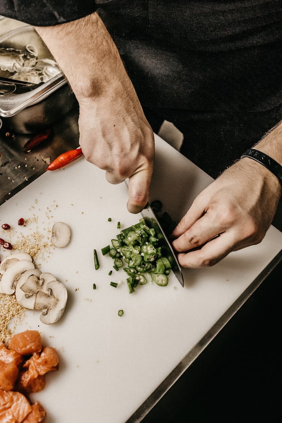 Les mains du chef ciselant les herbes sur la planche de la cuisine