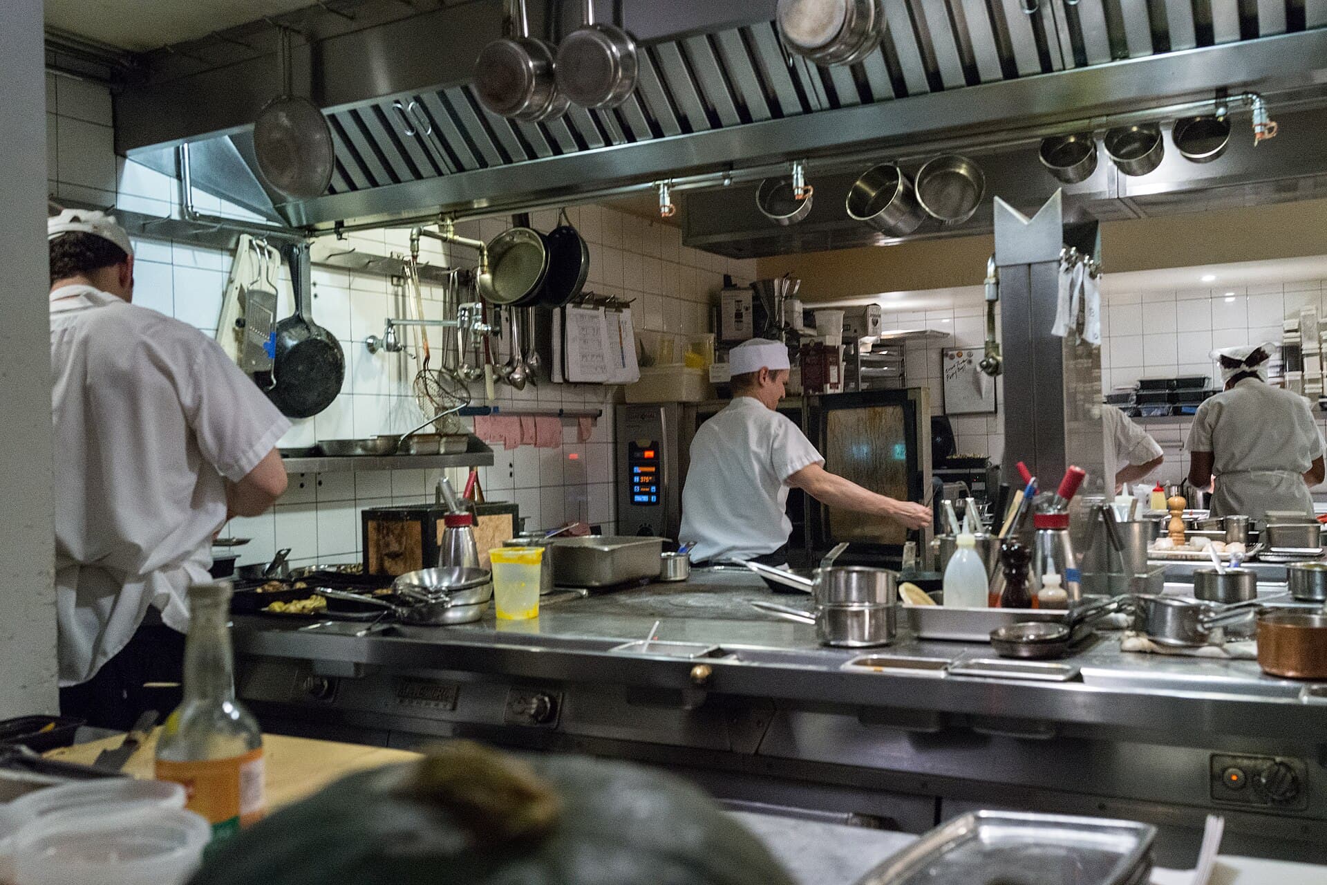 La brigade en plein service dans la cuisine, cuivres et inox sous les feux