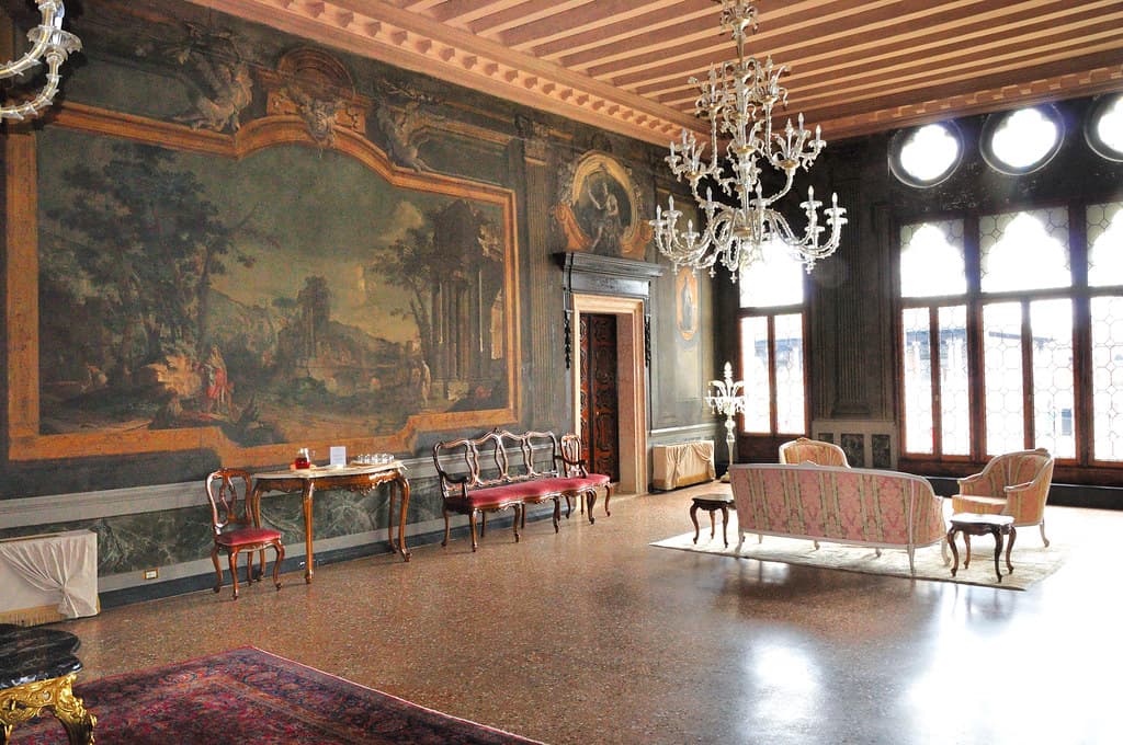 Grand salon privé aux boiseries sombres, lustre en verre soufflé et hautes fenêtres